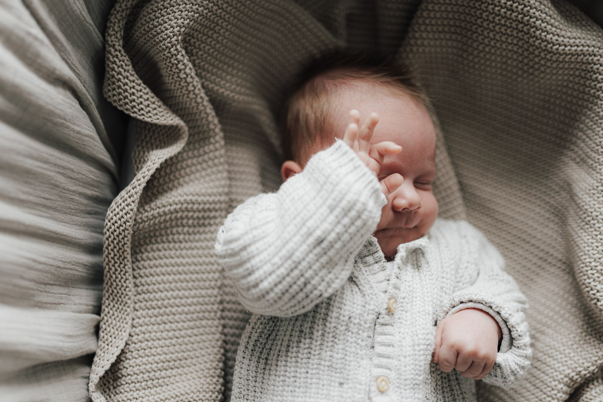 Baby liegt auf einer beigen Decke, fotografiert von Ansichtssach Fotografie