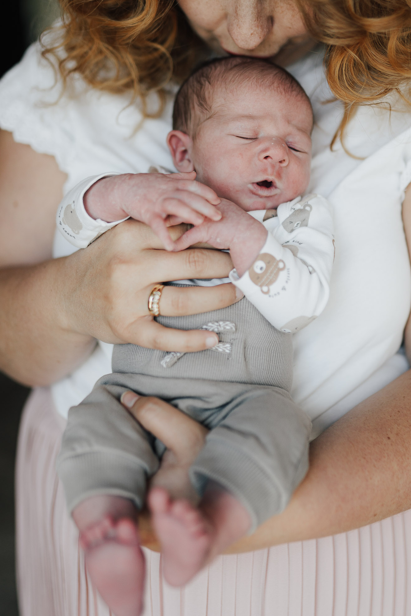 Frau hält Baby in den Händen, Neugeborenes schaut in die Kamera, fotografiert von Ansichtssach Fotografie